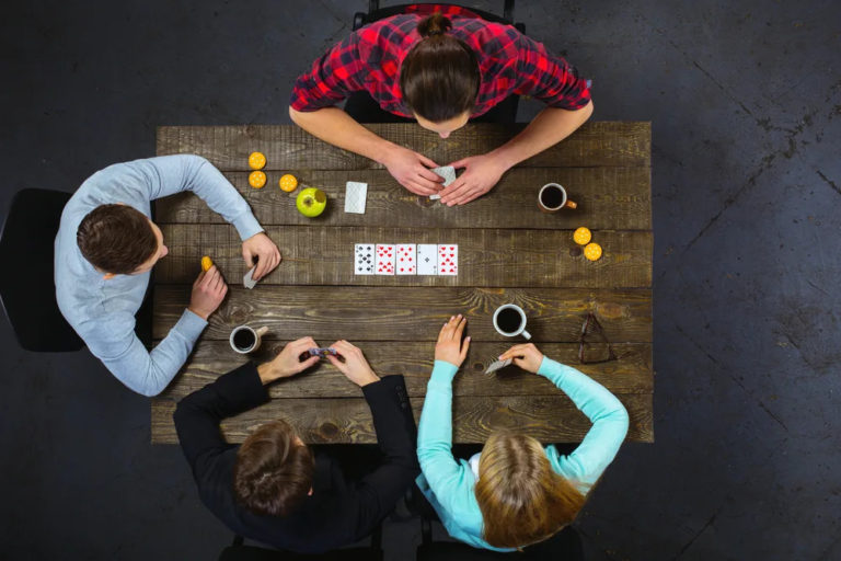 4 people siting on a table playing cards